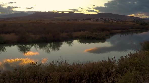 Panning time lapse of a sunset reflecting off the glassy surface of a river with mountains in the ba