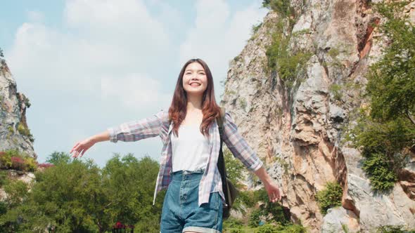 Cheerful young traveler Asian lady with backpack walking at the mountain lake.