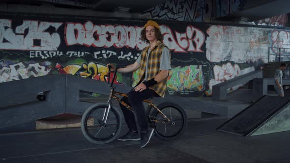 Positive Man Having Break After Training on Bmx Bike at Skate Park Graffiti