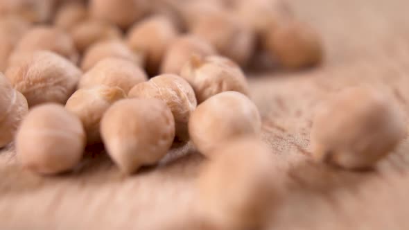 Macro shot of raw uncooked chickpeas falling onto a wooden surface from a white bowl