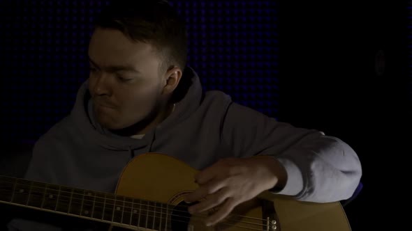 Portrait of a young man playing acoustic guitar