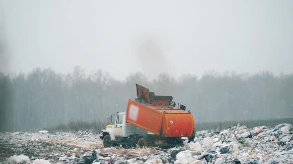 Orange Truck Working with Litter at a Dump.