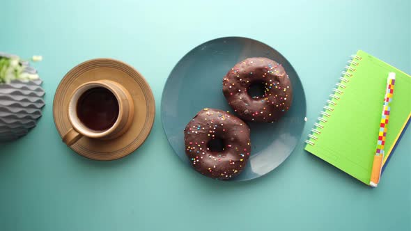Chocolate Donuts  Tea and Notepad on Table