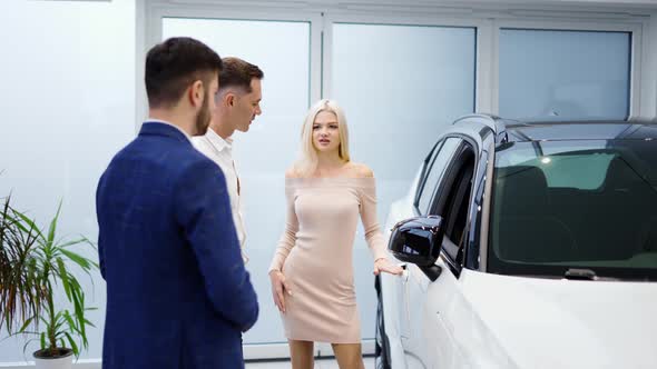 Pretty Young Elegant Couple Choosing Car in Dealership