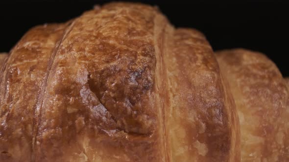 Croissant on white plate rotating in front of camera on black background