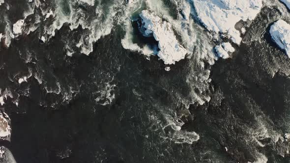 Aerial View of Godafoss Waterfall with Snowy Shore and Ice. Iceland. Winter 2019