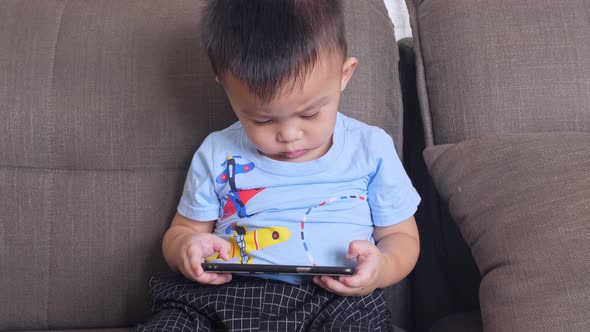 Cute Little Boy Watching Cartoons On Mobile Phone