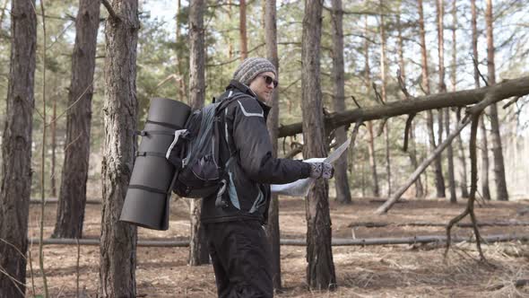 Orienteering in the forest. Tourist on a hike in a forest park with a map.