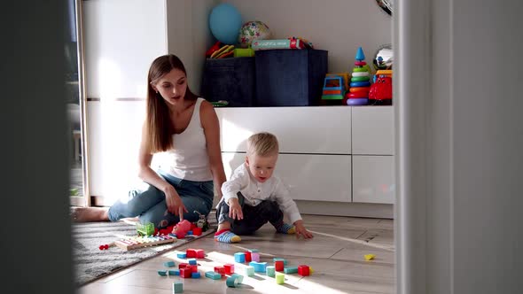 Little Cute Boy with His Mother Play with Toys at Home