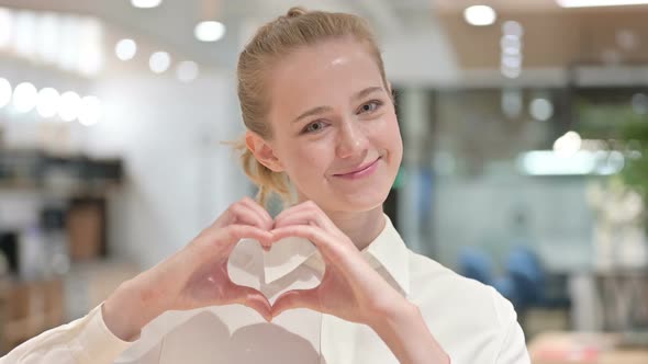 Portrait of Loving Young Businesswoman Showing Heart Sign with Hand 
