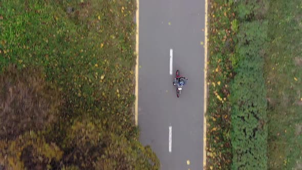 Aerial view Child riding bicycle in autumn park. Active sport family leisure.