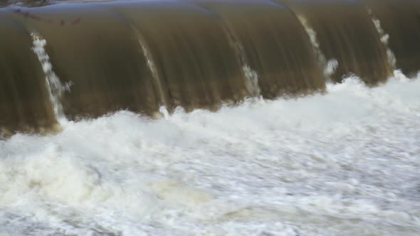 UHD Long shot of water rushing away from the base of a small waterfall during a spring melt