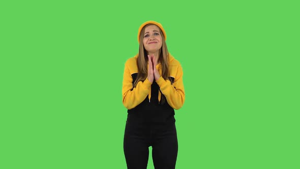 Modern Girl in Yellow Hat Is Keeping Palm Together and Asking for Something. Green Screen