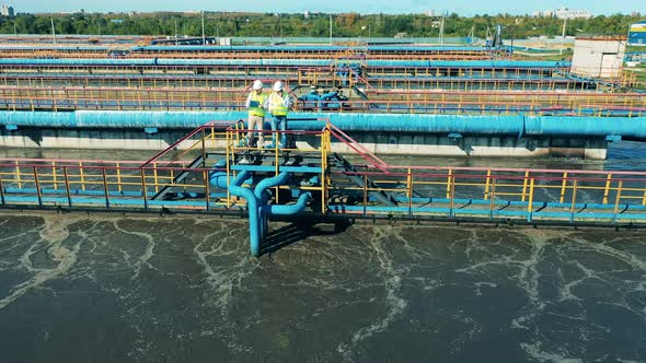 Aerial View of Two Workers Observing a Wastewater Treatment System