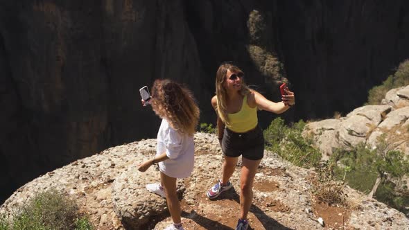 Joyful Women Stand on Rock Making Selfie Near Large Hole