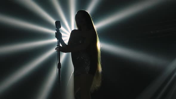 Bottom View is Silhouette of Female Vocalist in Short Dress Performing on Stage with Smoke