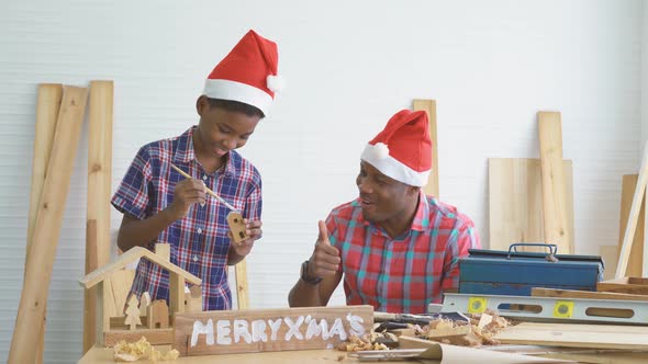 Happy father and little son playing and chatting while help painting wood house model together