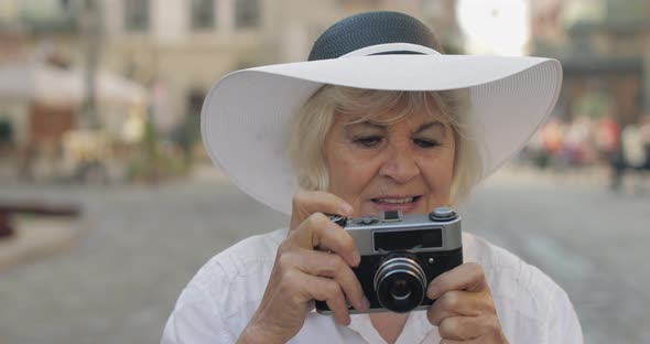 Senior Female Tourist Exploring Town and Makes a Photo with Retro Photo Camera