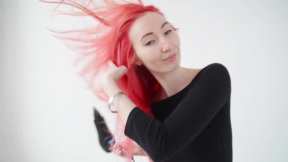 Concept of Coloring and Hair Care. Young Woman Dries Red Hair on a White Background