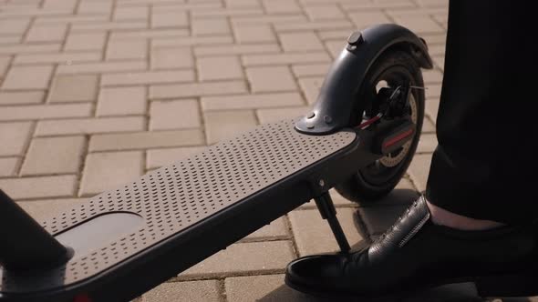 Close-up of a Businessman's Foot on an Electric Scooter in a Park.