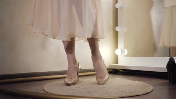 Close-up of Female Caucasian Feet in Elegant Beige High-heel Shoes Spinning in Dressing Room