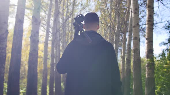 Photographer Goes with a Tripod in the Forest