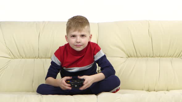 Little Boy with Games Console Playing Video Game on Couch