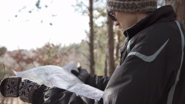 Orienteering in the forest. Tourist on a hike in a forest park with a map.