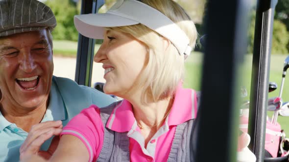 Two golfers driving in their golf buggy