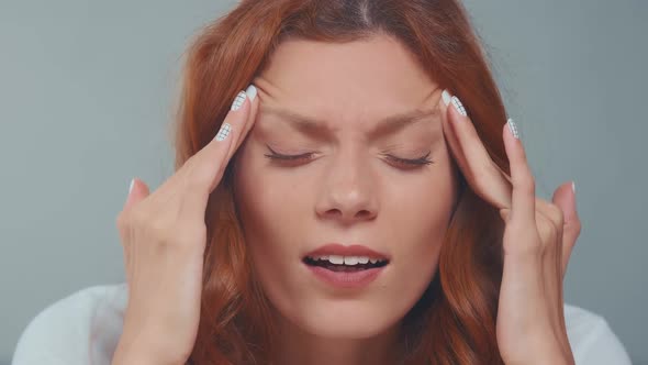 Close Up Redhead Woman with Closed Eyes Covered Face in Hands Feeling Pain