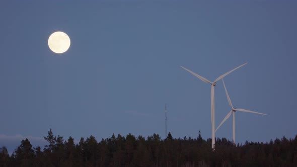 FULL MOON, SLOW MOTION - Wind turbines spin next to a rising full moon