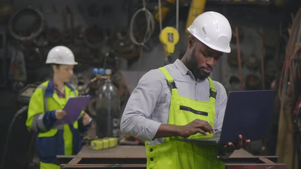 Afro Industrial Worker Checking Project Plan on Laptop