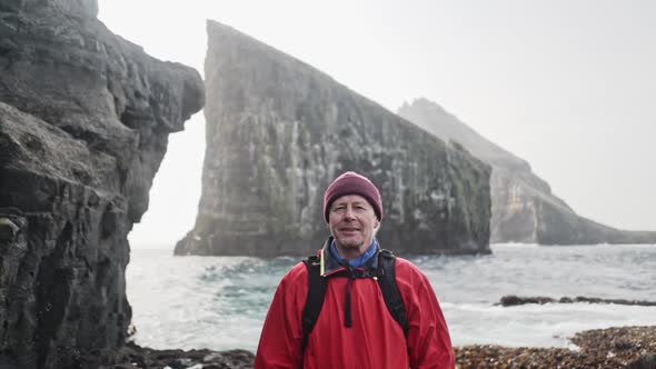 Portrait Shot of Male Traveler and Drangarnir Rocks and Ocean in Background