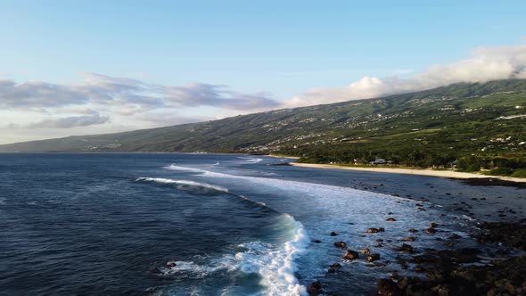 Drone footage of waves at the beach at the Reunion island during sunset.