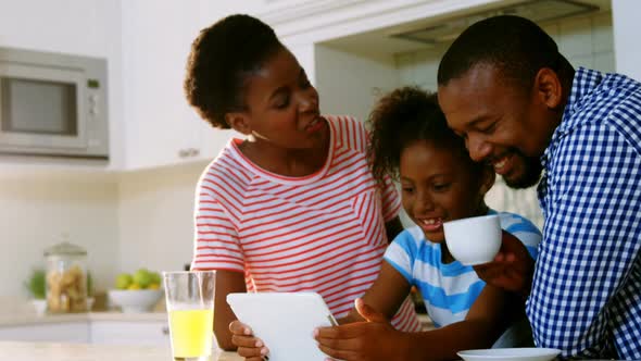 Parents and daughter using digital tablet in kitchen