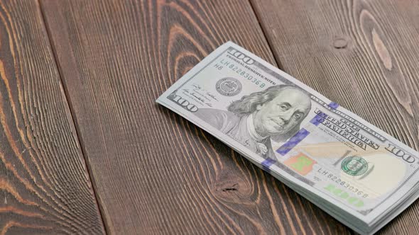 Stack of US Dollar Banknotes Dropping on Wooden Surface and Bouncing