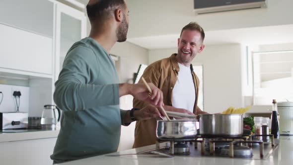 Multi ethnic gay male couple preparing food in kitchen