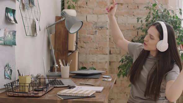 Woman Sitting at Desk and Dancing to Music