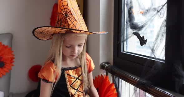 Cute Caucasian Little Girl with Blonde Hair Seven Years Old in Witch Dress and Hat Having Fun and