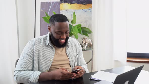 Busy Positive African American Man Manager Entrepreneur Sitting at a Desk in the Office Using His