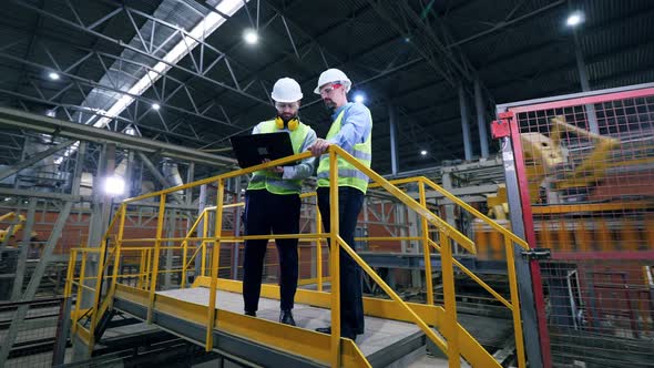 Engineers Work with a Laptop at a Modern Industrial Factory. Professional Factory Workers at Factory