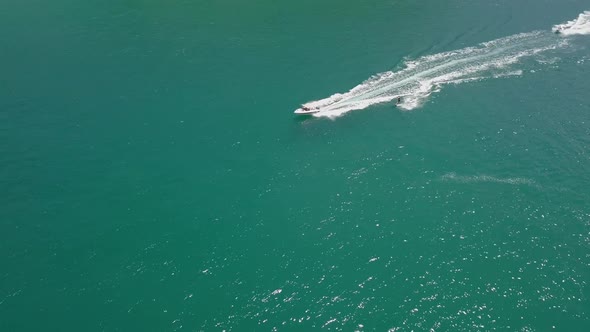 Tracking aerial: surfer waterskiing on beautiful jade-colored water