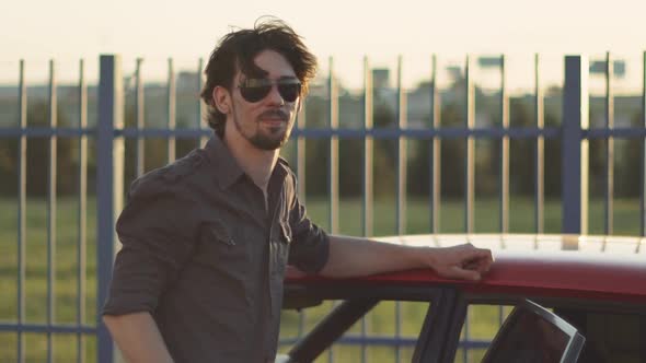 Portrait of Handsome Man with His Old Classic Powerful Car on Street at Sunset or Sunrise