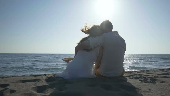 Couple Sitting on the Beach and Looking at the Sea