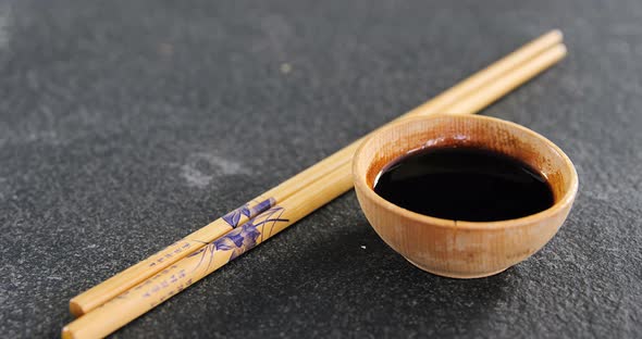 Chopsticks and soy sauce on black stone slate