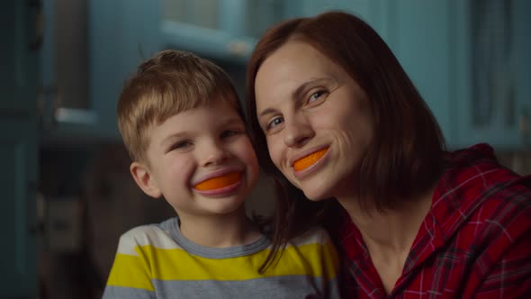 Funny family playing with orange peels in their mouth at home