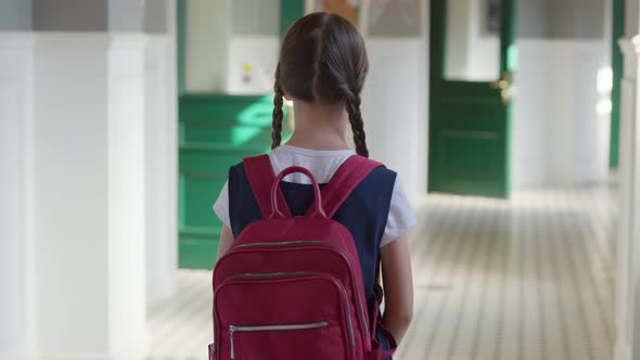 Dolly Push Shot of Caucasian Preteen Kid with Backpack Standing in Empty School Hall