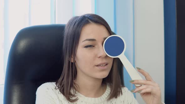 A Young Caucasian Woman in a Cozy White Sweater in the Ophthalmologist's Office at the Optics Clinic