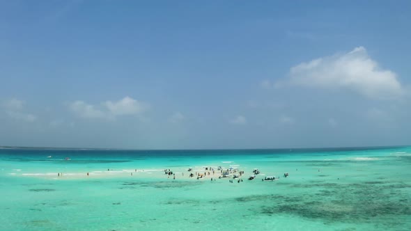 Anchored boats and people in shallow tropical ocean sandbank, Zanzibar.