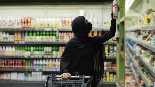 Woman in Hijab and Protective Mask Doing Shopping Takes Product From the Shelf Slow Motion